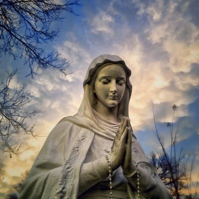 low-angle-view-of-virgin-mary-statue-against-cloudy-sky